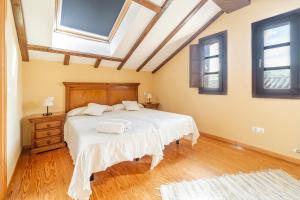a bedroom with a bed with white sheets and windows at Casa Rural De Cabrera in Urrez