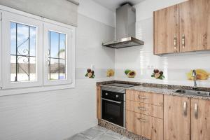 a kitchen with wooden cabinets and a stove top oven at Villa Montenmedio 2 in El Soto