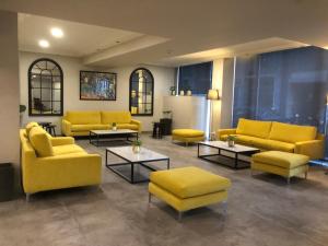 a living room with yellow couches and tables at Candia Hotel in Athens
