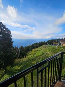 a balcony with a view of a green hill at The Smarthill Sanctuary in Dalhousie