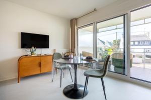 a dining room with a table and chairs and a large window at La pause iodée Studio -grand balcon in Concarneau
