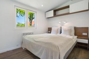 a white bedroom with a bed and two windows at Haus Waldblick in Saal