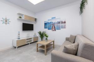 a living room with a couch and a tv at Victoria's Apartamentos Beach in Málaga