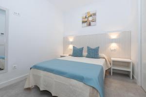 a bedroom with a large bed with blue pillows at Victoria's Apartamentos Beach in Málaga