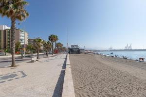 a sandy beach with palm trees and the ocean at Victoria's Apartamentos Beach in Málaga