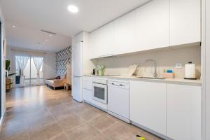 a kitchen with white cabinets and a living room at Mabicarent Playa 1 in Calafell