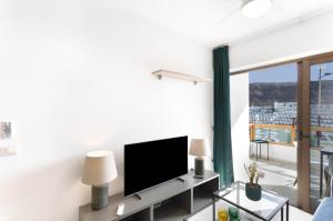 a living room with a flat screen tv next to a window at Casa Neale in Puerto Rico de Gran Canaria
