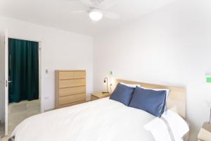 a bedroom with a large white bed with blue pillows at Casa Neale in Puerto Rico de Gran Canaria +18 photos