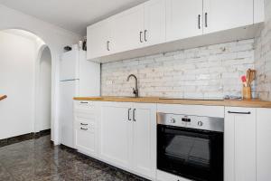 a kitchen with white cabinets and a black oven at El Cotillo Mar Beach in El Cotillo +19 photos
