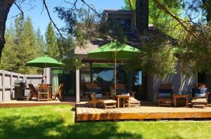 a deck with chairs and tables and umbrellas at 81 Meadow Lane in Sunriver