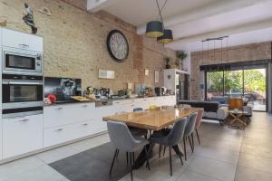 a kitchen with a wooden table and a clock on the wall at Bocal De Bages - Chez l'habitant in Bages