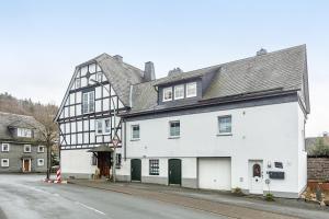 a white and black building on the side of a street at Ferienwohnung zum Heubalken in Schmallenberg