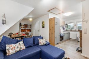 a living room with a blue couch and a kitchen at Ferienwohnung zum Heubalken in Schmallenberg