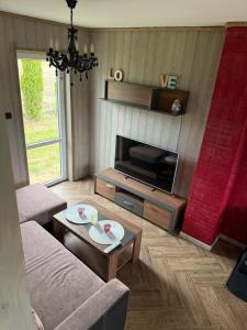 a living room with a couch and a tv at Bajkowe Domki Marzeń Grei in Węgorzewo