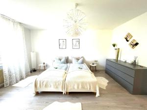 Un dormitorio blanco con una cama y una lámpara de araña. en Apartment Alb Glück 1, en Hechingen