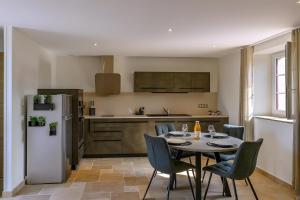 a kitchen with a table and chairs and a refrigerator at L'Ascalon in Saint-Sauveur-le-Vicomte