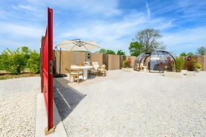 a patio with a table and a greenhouse at L'Ascalon in Saint-Sauveur-le-Vicomte