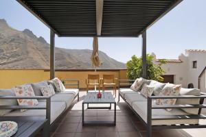 a patio with white couches and a table and mountains at La Suerte viviendas in Agaete