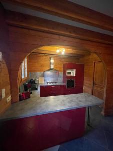 a kitchen with red cabinets and a large counter top at Le Chalet de Noblat in Saint-Léonard-de-Noblat +2 photos