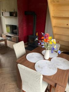 a wooden table with plates and a vase of flowers on it at Bajkowe Domki Marzeń Grei in Węgorzewo +6 photos