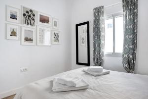 a white bedroom with two towels on a bed at Ula Home in Barbate