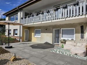 a patio with a couch and an umbrella in front of a house at Haus Alb-Apfel in Apfelstetten