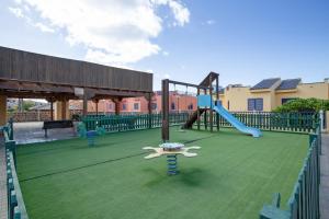 a playground with a slide on a green lawn at Bahia Meloneras Luxury Duplex in Maspalomas