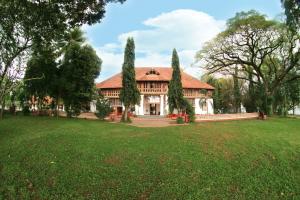 uma casa grande com árvores no quintal em Bolgatty Palace & Island Resort em Cochin