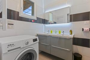 a bathroom with a washing machine and a sink at Les Sables in Bormes-les-Mimosas