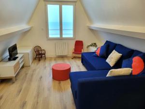 a living room with a blue couch and a window at L'hermitage, Villa Front De Mer in Pirou