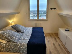 a bedroom with a bed with a blue comforter and two windows at L'hermitage, Villa Front De Mer in Pirou