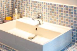 a white sink in a bathroom with blue tiles at Maison de pêcheur au Rosmeur in Douarnenez