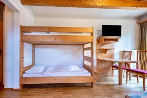 a bunk bed in a room with a desk and a tv at Lindenhof Apt 3 in Vandoies +6 photos