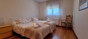 a bedroom with two beds and a chair and a window at Casa La Marina in Llanes