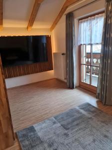 a living room with a large flat screen tv and a large window at Ferienwohnung Wetterstein in Mittenwald