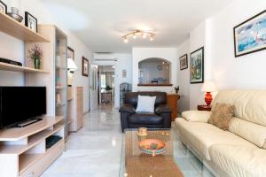 a living room with a couch and a tv at Mi capricho Beachfront Apt in Mijas
