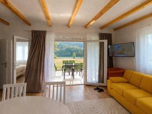a living room with a yellow couch and a table at Kucica na Drini MINJA in Višegrad