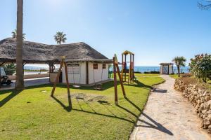 a playground in front of a building with the ocean at Mi capricho Beachfront Apt in Mijas