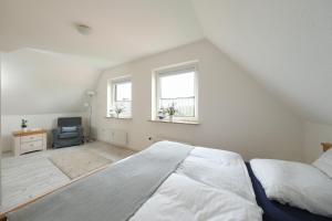 a white bedroom with a large bed and two windows at Ferienwohnung Barsch in Rade