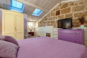 a bedroom with a purple bed and a tv on a dresser at Alghero Old Town Gem - Sardinia in Alghero