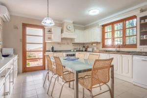 a kitchen with white cabinets and a table and chairs at Villa Costa De Blanes in Calvià