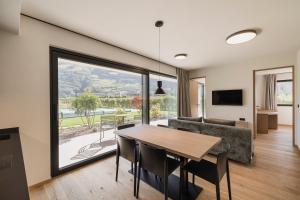 a dining room and living room with a table and a couch at Trianglhof surrounded by vineyards in Bolzano