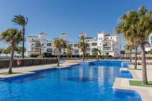 a swimming pool with palm trees in front of condos at Casadeluxe Riquelme in Sucina
