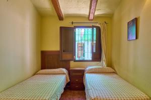 two beds in a small room with a window at Rivero Rural in Rivero de Posadas