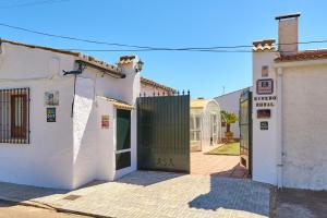 a white building with a green door on a street at Rivero Rural in Rivero de Posadas