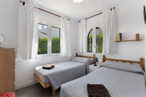 two beds in a room with two windows at La Gardenia 41 in Es Castell +16 photos