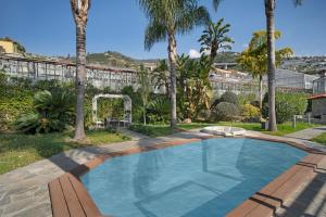 a swimming pool in a yard with palm trees at Villa Vallegrande in Ospedaletti
