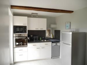 a kitchen with white cabinets and a stainless steel refrigerator at Studio Les Restanques in Montbrun-les-Bains