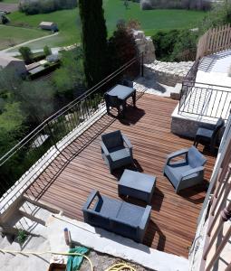 a wooden deck with chairs and tables on it at Studio Les Restanques in Montbrun-les-Bains