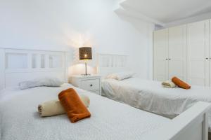 a white bedroom with two beds with towels on them at Ático deluxe Corralejo centro in Corralejo